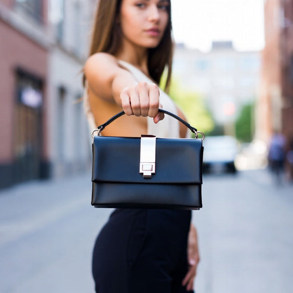 Woman holding a black handbag on a city street
