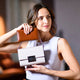 Woman holding two handbags in a blurred indoor setting